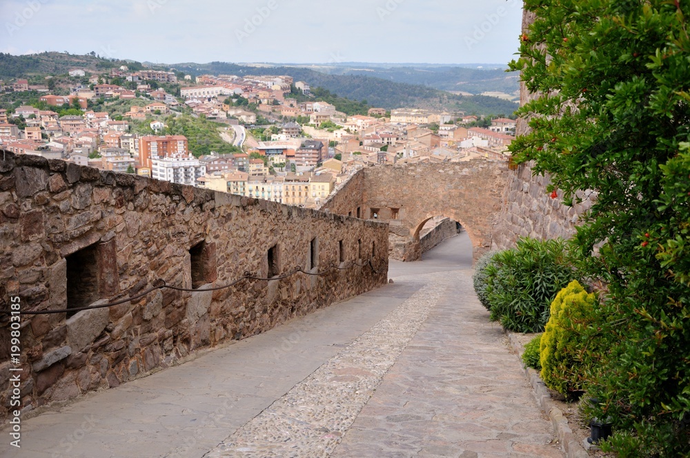 Entrance of Cardona Castle. Stone walls and road.