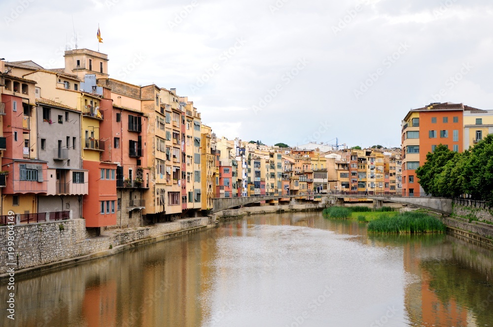 Colorful houses, reflected in the water of the river Onyar. View from the Red iron bridge or Girona Eiffel Bridge (Pont de les Peixateries velles). The historic Jewish quarter in Girona, Spain. 