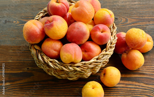 Fresh Apricot in the basket on wooden background photo