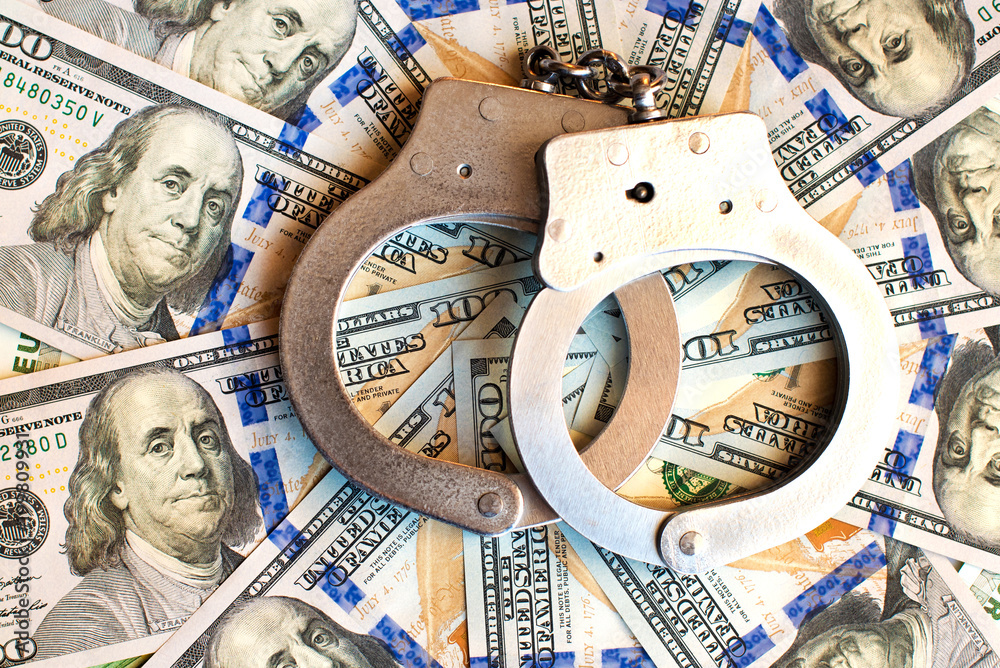 Dollars and handcuffs as an abstract symbol of financial crimes and corruption of officials and politicians Dollars and handcuffs as an abstract symbol of financial crimes and corruption of officials and politicians