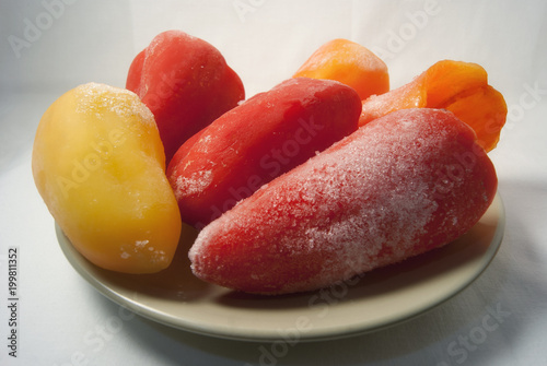 Frozen red yellow bell peppers paprika on a plate white background photo