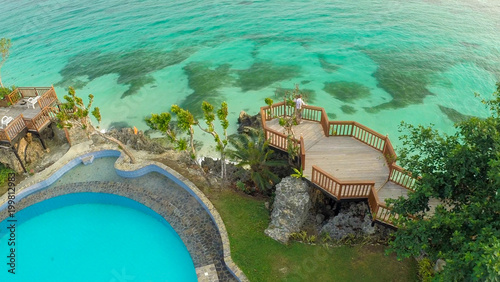 A beautiful light green coast with reefs and a loving couple on the balcony above the beach. The beautiful nature of the Philippines. Aerial view. Near open pool. photo