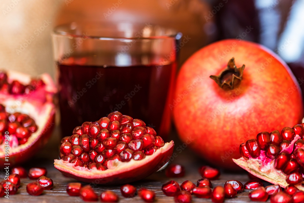 Ripe pomegranates with glass of juice on table Ripe pomegranates with glass of juice on table