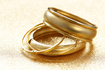 gold jewelry bracelets on gold background