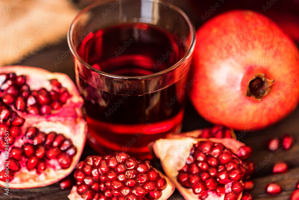 Ripe pomegranates with glass of juice on table Ripe pomegranates with glass of juice on table