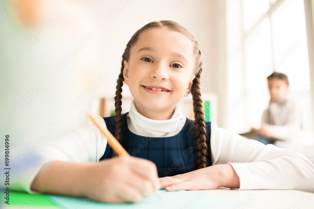 Portrait of cute schoolgirl writing at the table at school Portrait of cute schoolgirl writing at the table at school