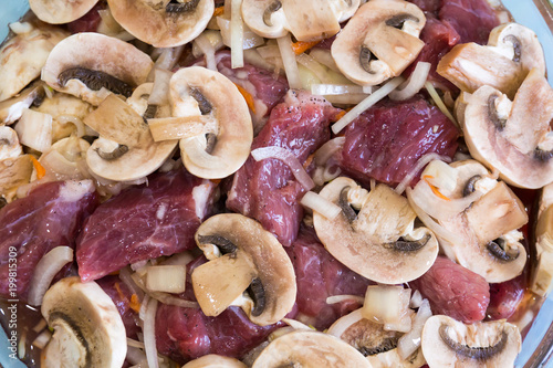 Preparation of beef with mushrooms and onions. Raw meat.