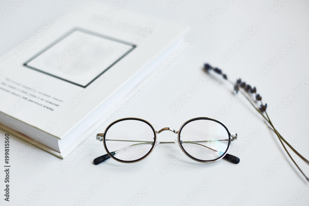 Glasses on a glossy white table next to the book Glasses on a glossy white table next to the book
