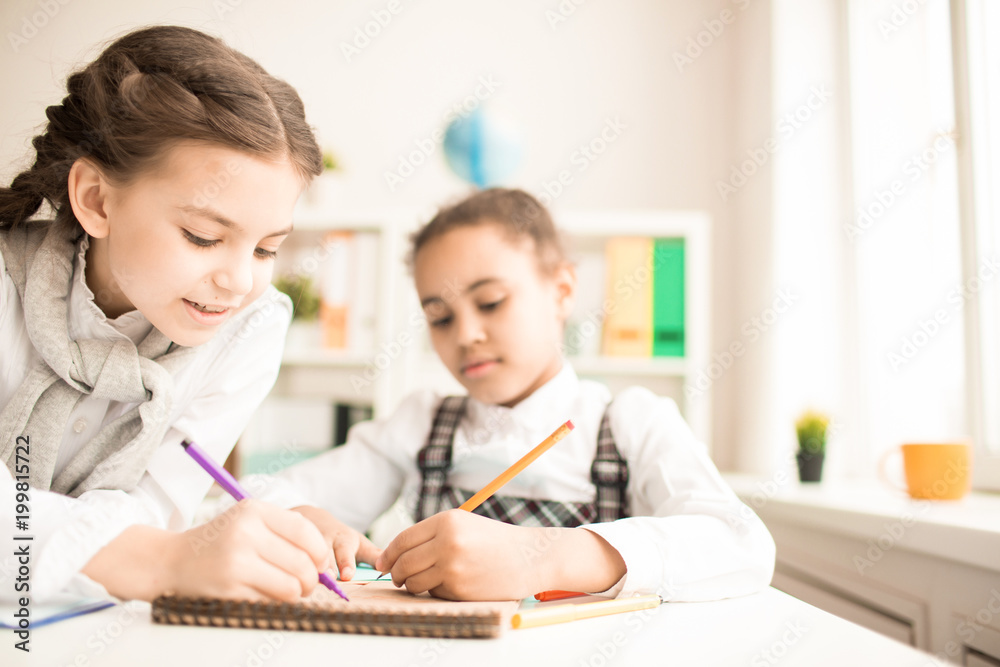 Two schoolgirls drawing together in notepad at classroom Two schoolgirls drawing together in notepad at classroom