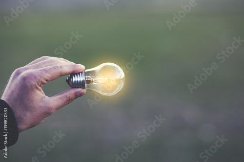Man hand holding glowing light bulb