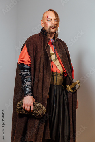 Severe warrior Russian Cossack, face in scars, bald. Bled blood. Saber in sheath.