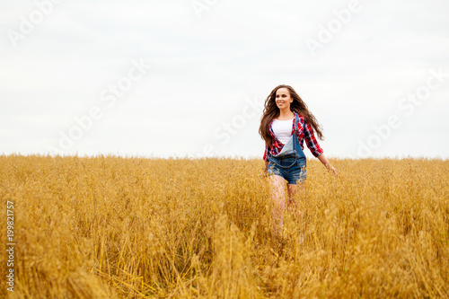 Young beautiful woman walking in a field, summer outdoors