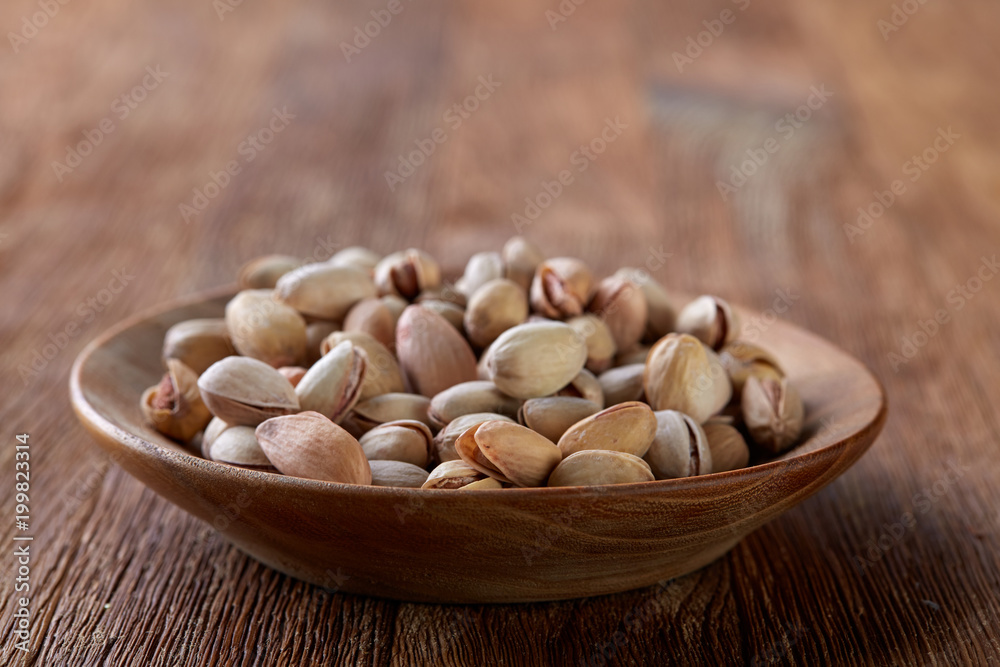 Almonds in brown bowl on wooden background, top view, selective focus. Almonds in brown bowl on wooden background, top view, selective focus.