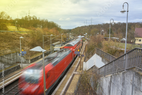 Rote Eisenbahn fährt durch Bahnhofstation in voller Geschwindigkeit
