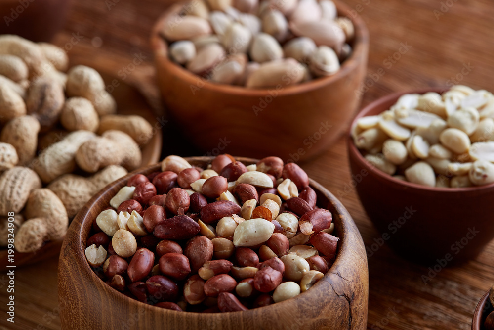 A composition from different varieties of nuts in a wooden bowls on rustic background, close-up, shallow depth of field A composition from different varieties of nuts in a wooden bowls on rustic background, close-up, shallow depth of field