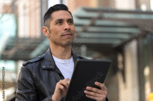 Hispanic man in city using tablet computer