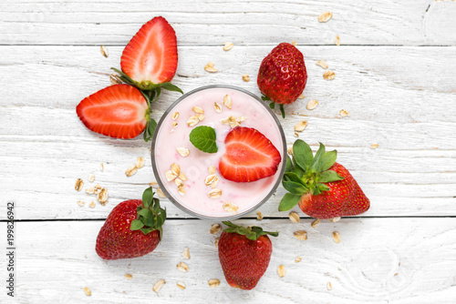 strawberry yogurt in a glass with fresh berries, oats and mint on white wooden background. healthy breakfast.