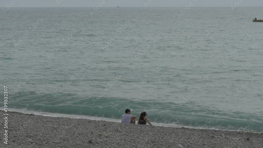 A man and a woman sitting on a beach A man and a woman sitting on a beach