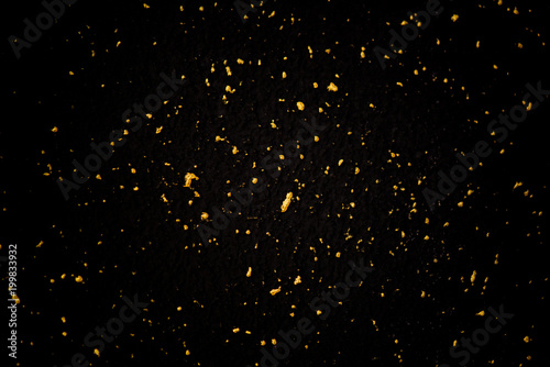 Gold glitter texture on a black background. Holiday background. Golden explosion of confetti. Golden grainy abstract texture on a black background. Design element. photo