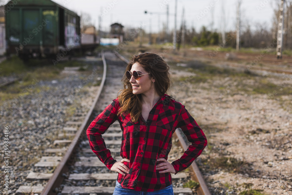 young beautiful woman wearing casual clothes, walking by the railway and smiling. Outdoors lifestyle. Travel concept.