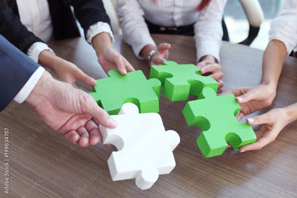 Business people assembling puzzle Business people assembling puzzle