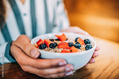 Crop woman close up eating oat and fruits bowl for breakfast