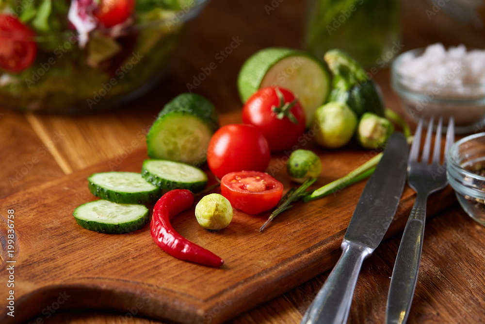 Fresh vegetable salad and ripe veggies on cutting board over wooden background, close up, selective focus Fresh vegetable salad and ripe veggies on cutting board over wooden background, close up, selective focus