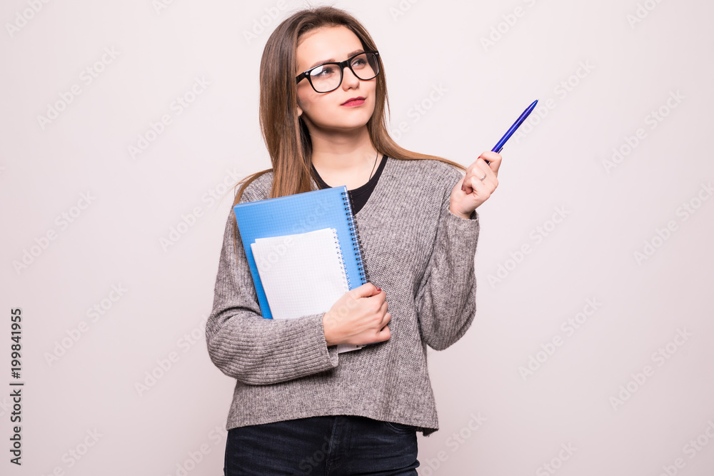 Portrait of a happy teenage girl with backpack holding books while standing and pointing finger up at copy space isolated over white Portrait of a happy teenage girl with backpack holding books while standing and pointing finger up at copy space isolated over white
