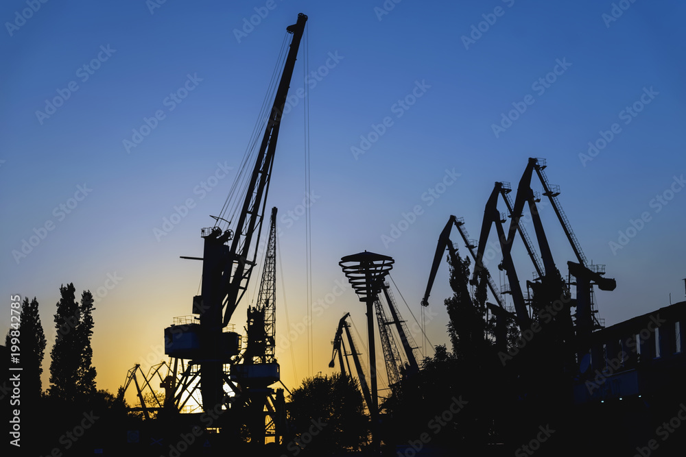 Evening in port, sea, river dock. Silhouette of industrial cranes. Wharf, Port landscape. Bright sunset