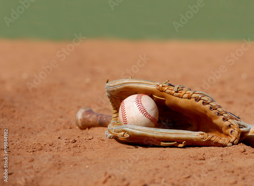 Sticker An old baseball glove cradling a worn ball lays in the dusty clay of the infield at a ball park on a sunny day