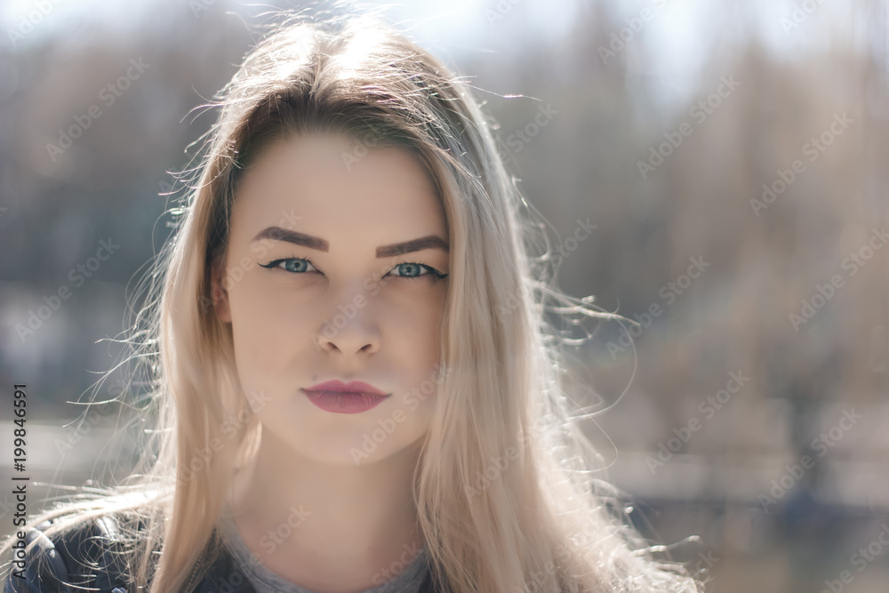 Outdoors portrait of beautiful young brunette girl. Woman smiling happy on sunny summer or spring day outside on city background. Close-up portrait in a golden hour. Selective focus. Outdoors portrait of beautiful young brunette girl. Woman smiling happy on sunny summer or spring day outside on city background. Close-up portrait in a golden hour. Selective focus.