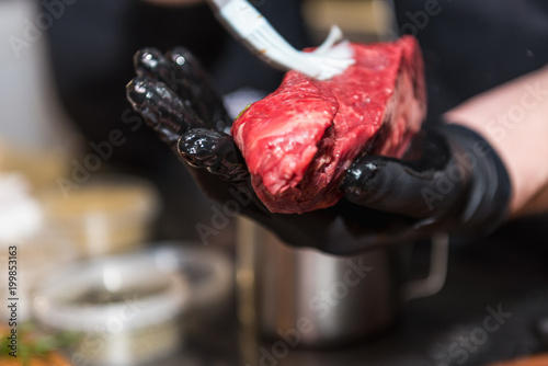 The hands of the chef lubricate raw meat photo