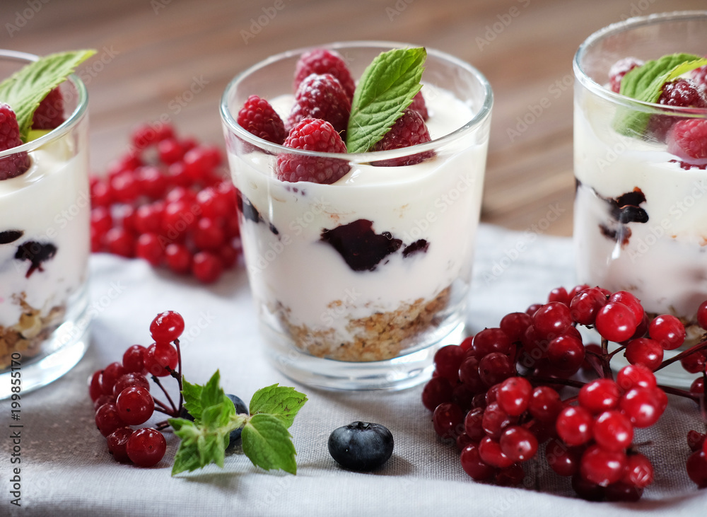 Healthy breakfast - yogurt with fresh berries and muesli served in glass jar, on wooden background Healthy breakfast - yogurt with fresh berries and muesli served in glass jar, on wooden background