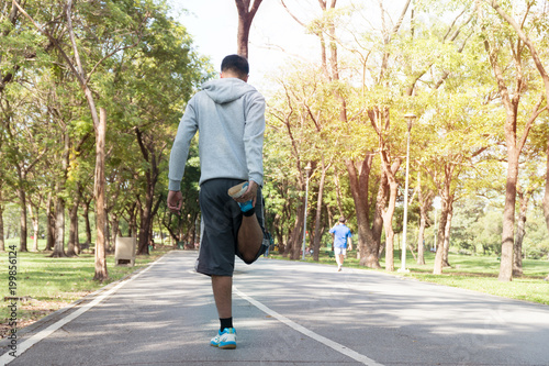 The back of yong man sportswear doing stretching exercise relaxing and warm up after jogging and running in park with copy space. sport, lifestyle concept