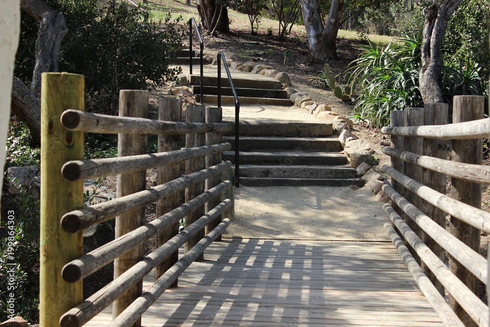 An old wooden bridge leads to steps and a walking path