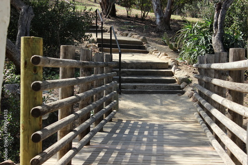 An old wooden bridge leads to steps and a walking path