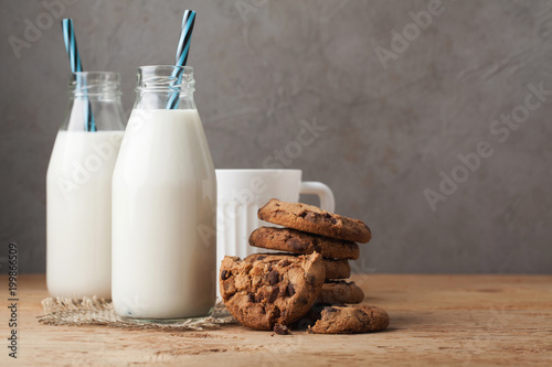 Two bottles of milk and chocolate chip cookies on dark background with copy space photo