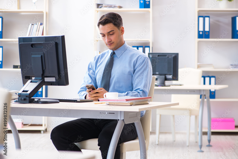 Handsome businessman employee sitting at his desk in office Handsome businessman employee sitting at his desk in office