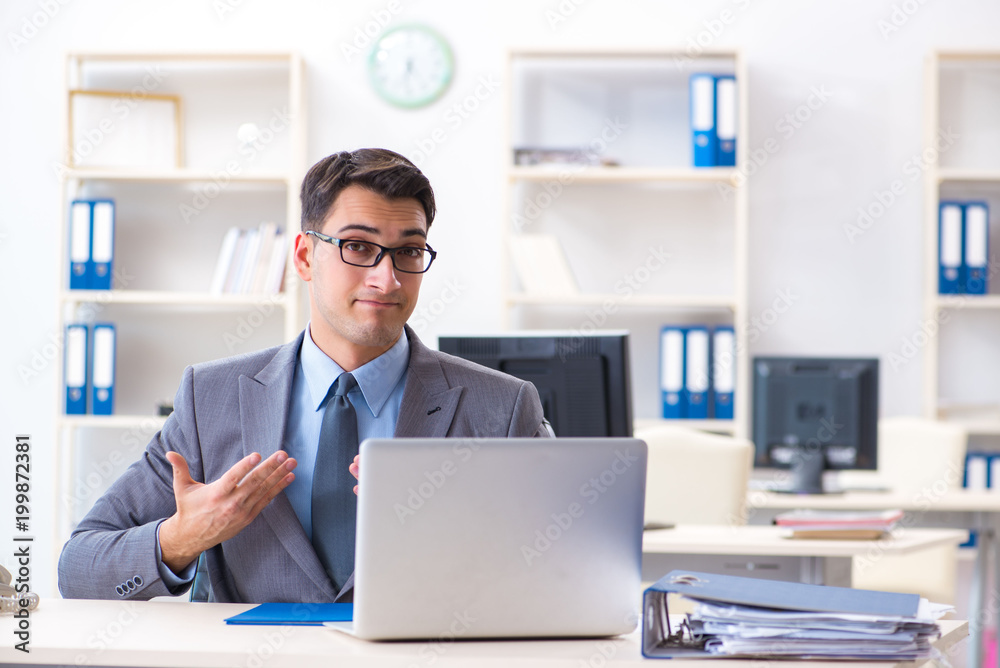 Handsome businessman employee sitting at his desk in office Handsome businessman employee sitting at his desk in office