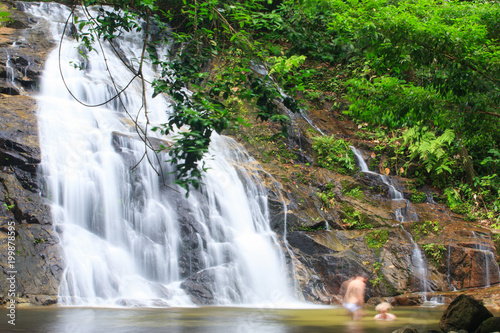 Senior European tourists relaxing by tropical waterfall.