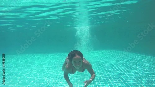 Young pretty woman jumps in swimming pool and swims underwater. 1920x1080
