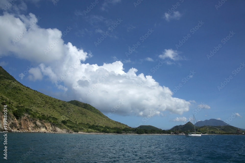 View of the coastline from the sea with a sailing boat, St Kitts, Caribbean.