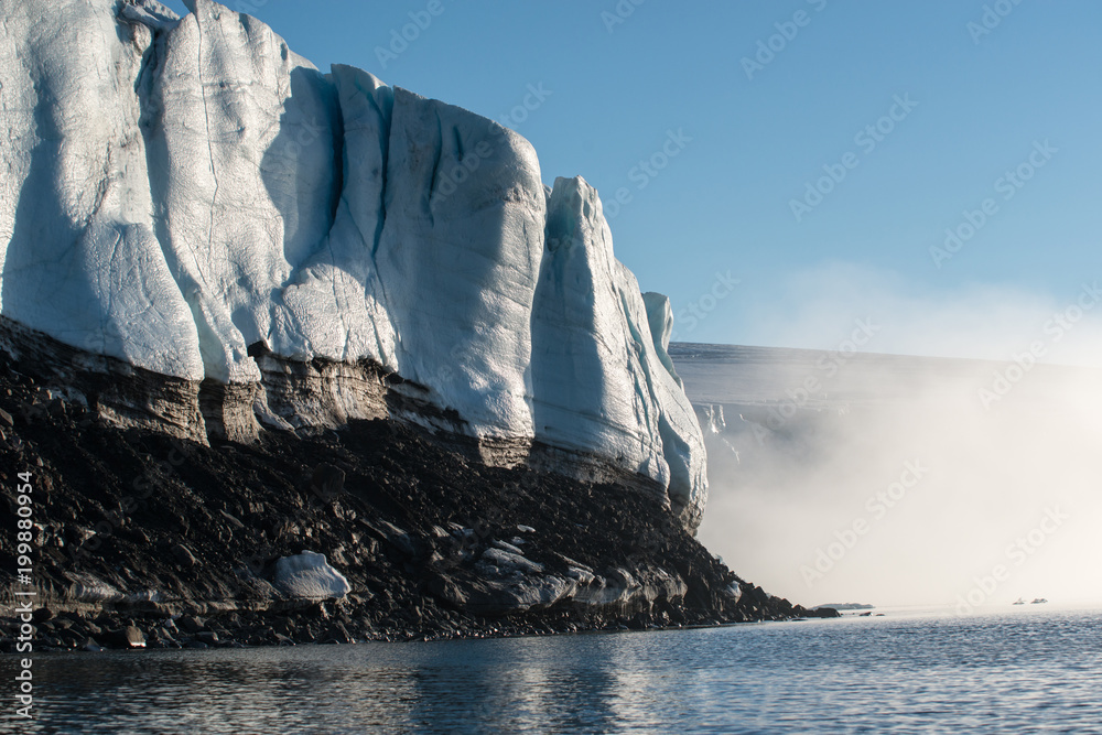 Φωτογραφία The glacier wall in the Arctic, the volcanic base from the bottom, the dome of the glacier in the background, the fog