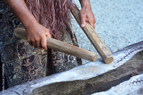 Fotografia Cook Islander man plays on a large wooden log Pate drum instrument