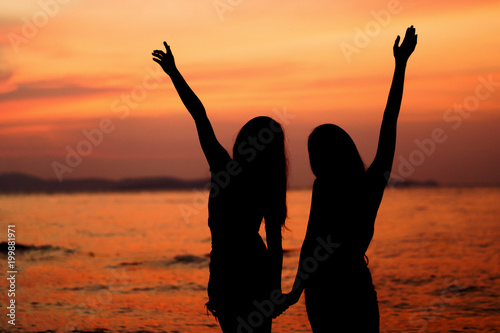 Silhouette of two woman having fun on the sea beach