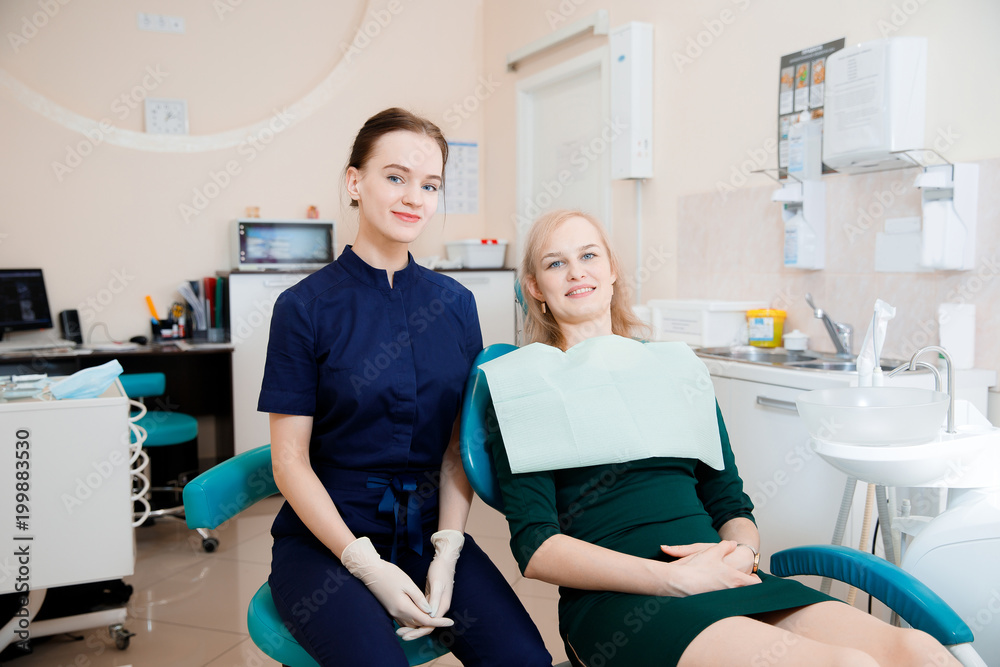 Dentist young woman in mask sits in dentistry next to patient.