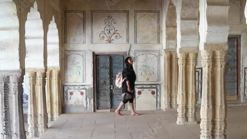 Woman tourist walking around pillars columns interior architecture traditional Indian motif doors wood stone handmade ethnic old art design of an old medieval static wide shot lock down  