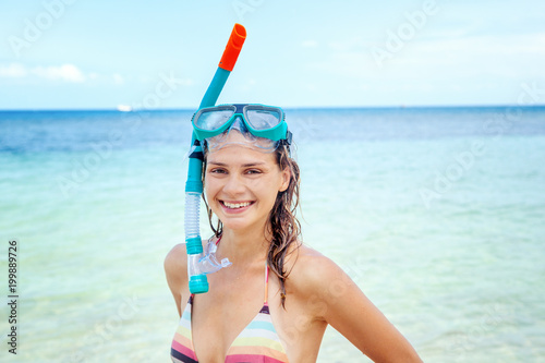 Beautiful young woman in a snorkeling mask on a background of azure sea, traveling to southern tropical countries