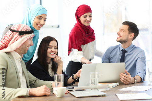 Office employees and their Muslim coworkers having business meeting in office