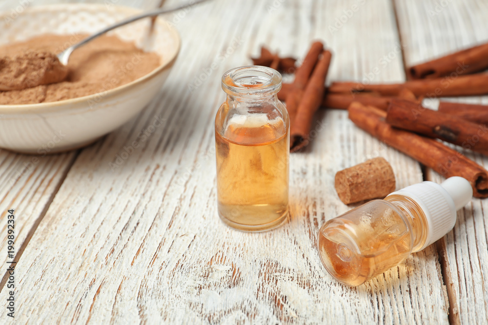 Bottles with cinnamon essential oil on wooden table Bottles with cinnamon essential oil on wooden table